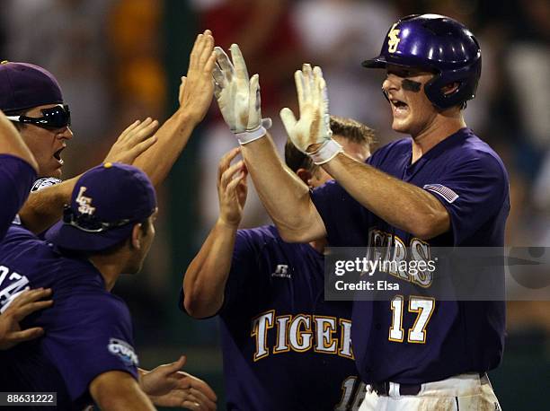 LeMahieu of the Louisiana State University Tigers is congratulated by teamamtes after he scored the game winning run off a hit by Mikie Mahtook in...