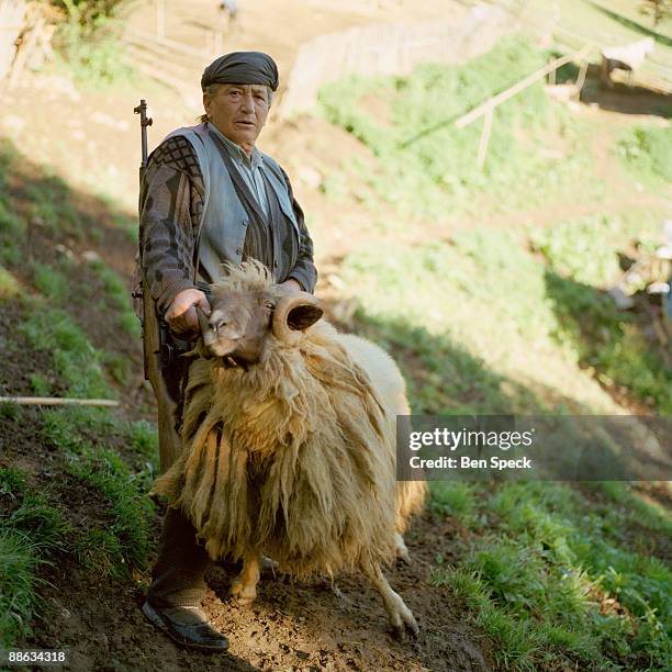 Kajtaz Lajci, aged 64, stands with her gun and her ram on her and her brothers' farm in Gjolaj. Being a sworn virgin gives her the otherwise...