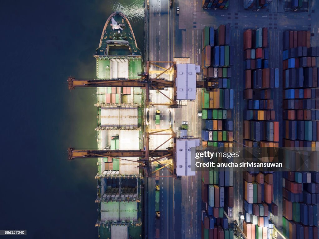 Harbor crane being Loading on container ship in warehouse port at night .