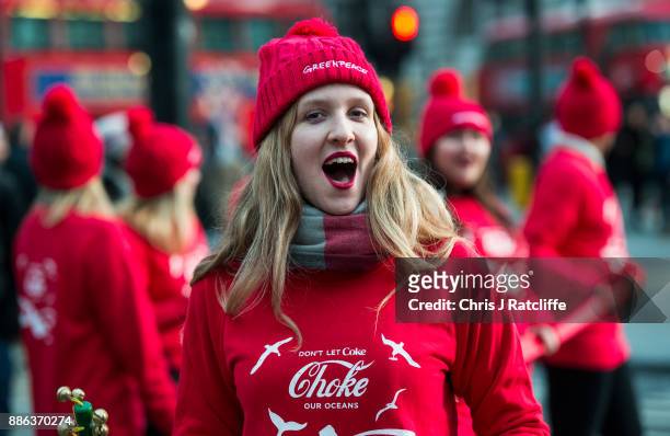 Greenpeace activists sing as they hold a demonstration in front of the Piccadilly Circus electronic billboard as part of a global campaign to get...
