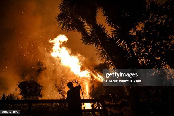 Al Galileo helps water down a backyard of a stranger's home as brush fire encroaches on the property on December 5, 2017 in Ventura, California.