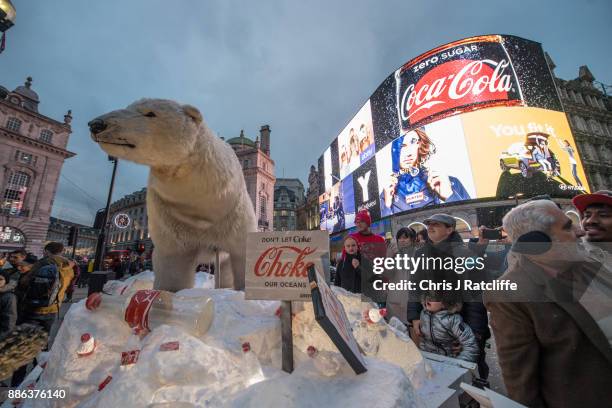 People watch as Greenpeace activists hold a demonstration in front of the Piccadilly Circus electronic billboard as part of a global campaign to get...