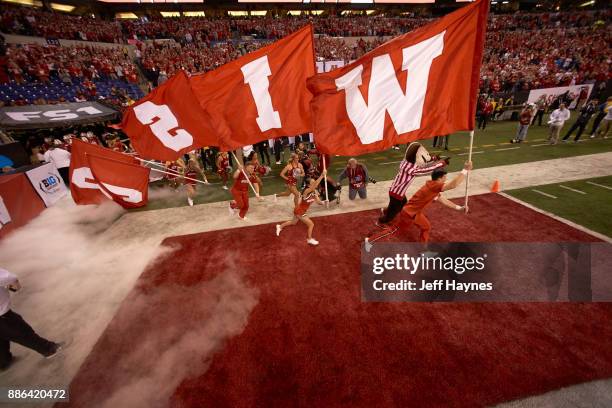 Big 10 Championship: Wisconsin cheerleaders taking field carrying flags that spell out WISCONSIN with mascot Bucky Badger before game vs Ohio State...