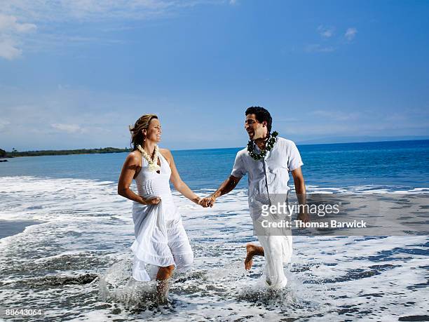 wedding couple running through water on beach - ankle deep in water fotografías e imágenes de stock