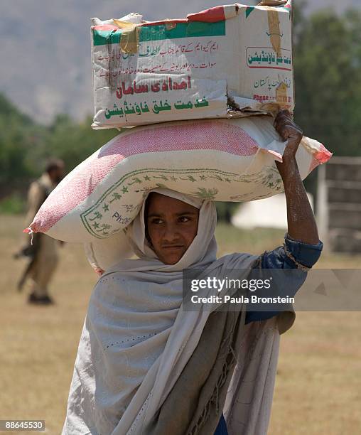 Pakistani woman carries flour on her head after receiving handouts from military sponsored food distribution, during a media visit to the area June...