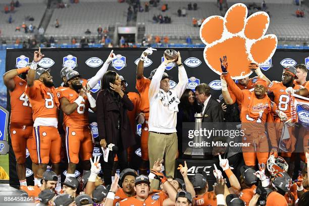 Head coach Dabo Swinney of the Clemson Tigers celebrates on the awards stand with his team while holding up part of the ACC Football Championship...