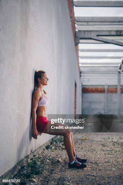 happy athletic woman doing wall sit on a sports training. - crouching stock pictures, royalty-free photos & images