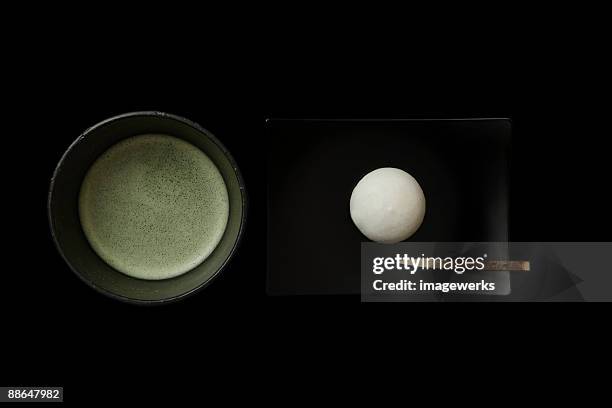 matcha (japanese powdered green tea)   with cake against black background, close-up - japanese sweet stock-fotos und bilder