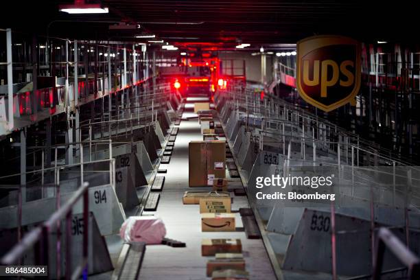 Packages move along a conveyor belt between rows of outgoing truck bays at the United Parcel Service Inc. Chicago Area Consolidation Hub in Hodgkins,...