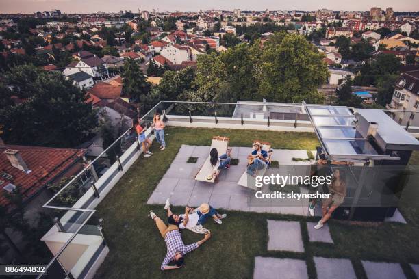 boven weergave van gelukkige vrienden ontspannen op het balkon van een penthouse. - penthouse stockfoto's en -beelden