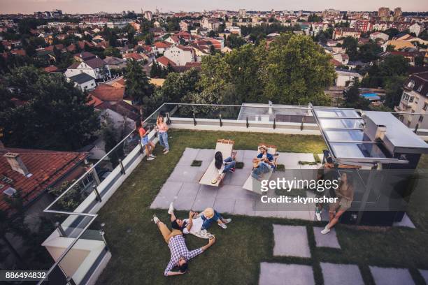 above view of happy friends relaxing on a penthouse balcony. - geographical locations stock pictures, royalty-free photos & images