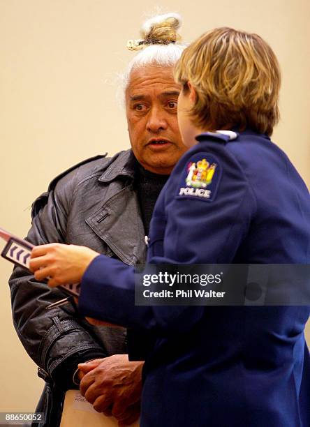 Defendant Gerrard Otimi speaks to a police officer as he appears in court on charges of deception at Manukau District Court on June 24, 2009 in...