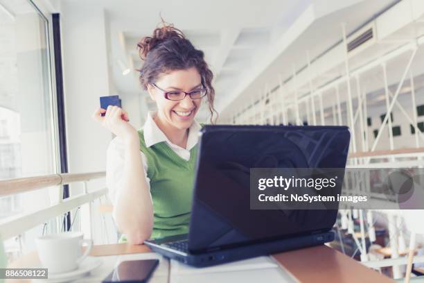 single. curly, red hair young woman, drinking coffee, making online shopping on laptop in cafe - curly red hair glasses stock pictures, royalty-free photos & images