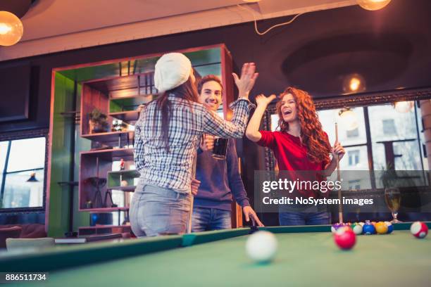 freunde, die einen spaß beim spielen billard in einer kneipe. - anstossen stock-fotos und bilder