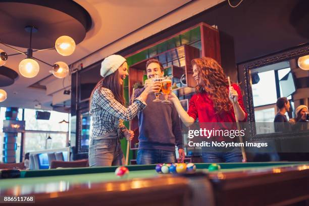 friends having a fun while playing billiard in a pub, toasting with beer. - snooker break stock pictures, royalty-free photos & images