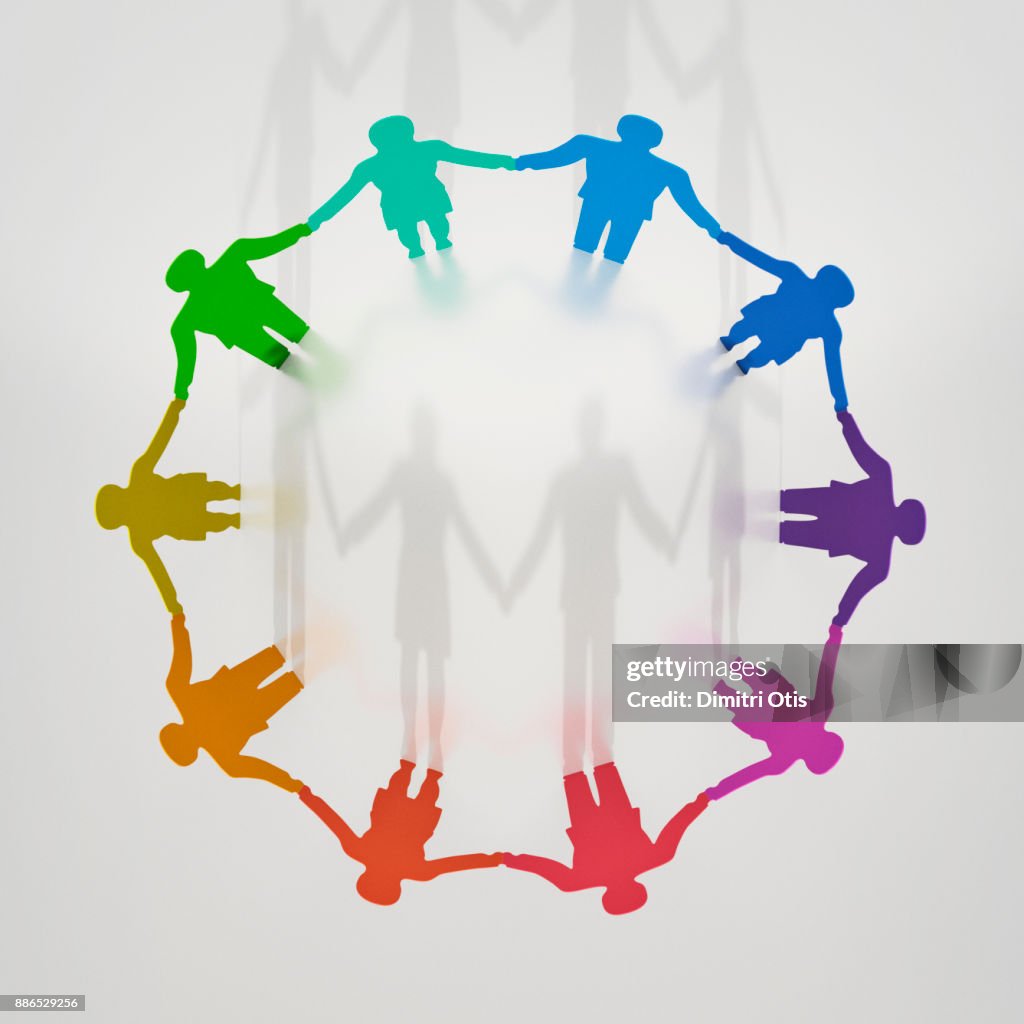 Circle of paper cut out couples, one couples shadow cast into centre