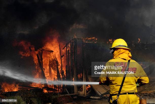 Firefighters battle strong winds as they try to save a house during the Thomas wildfire in Ventura, California on December 5, 2017. - Firefighters...