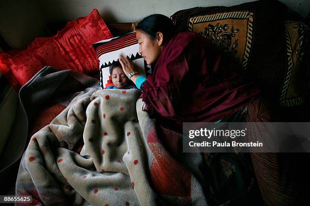 Khagendra Thapa Magar, 15 and a half, takes a nap as Dhan Kumari who is his manager's wife, acting as his second mother, brushes his forehead on...
