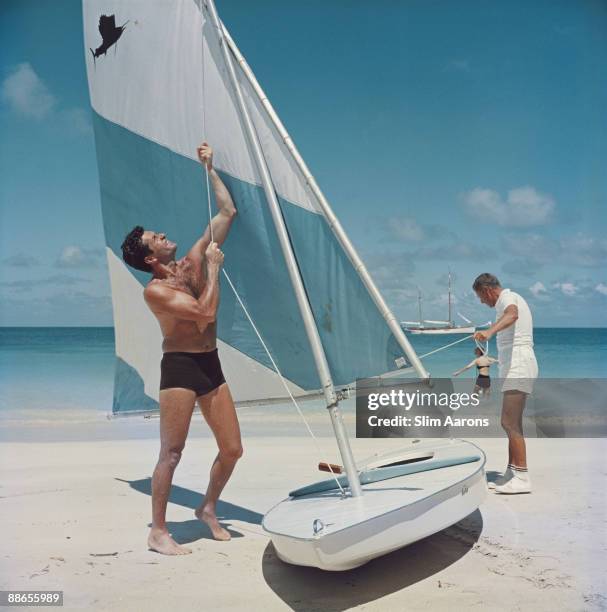 American actor Hugh O'Brian hoists the sail on a dinghy, Antigua, West Indies, 1961.