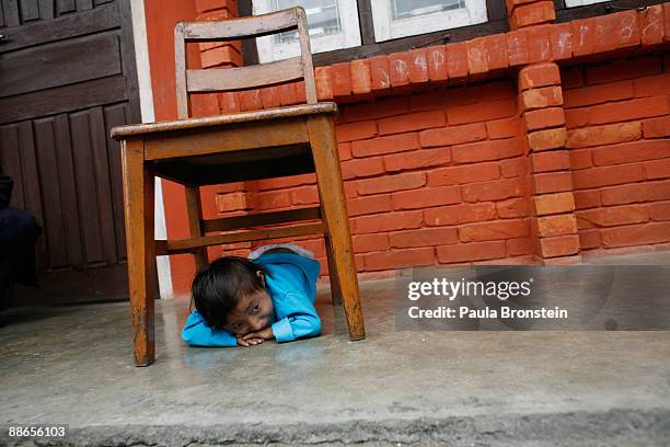 Khagendra Thapa Magar, 15 and a half, hides under a chair playing a game on March 13, 2007 in Pokhara, Nepal. According to the Guinness World Book of...
