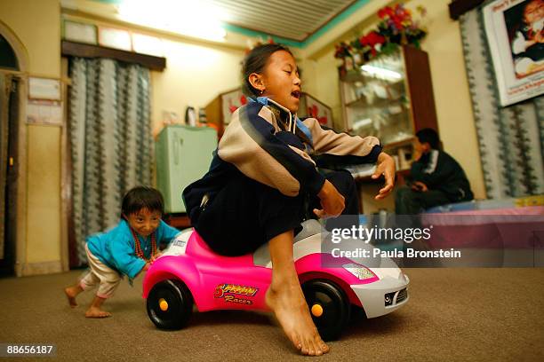 Khagendra Thapa Magar, 15 and a half, pushes family friend Sabina around the living room on a toy car on March 13, 2007 in Pokhara, Nepal. According...