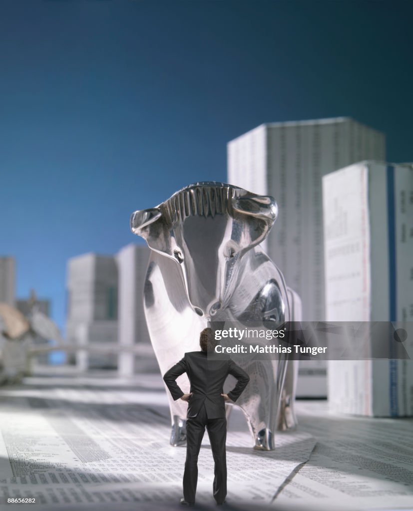 Business man facing bull in finance city