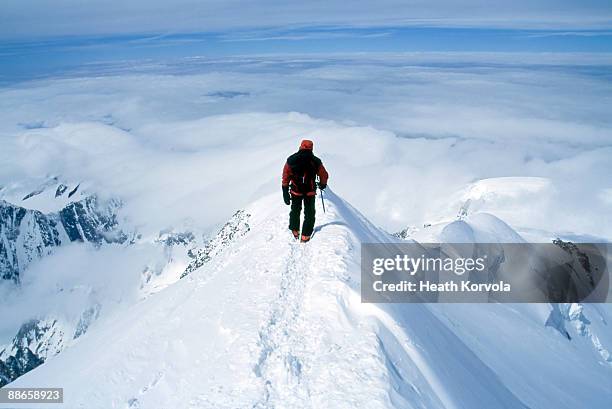 climber on steep summit of mountain in snow. - pico fotografías e imágenes de stock