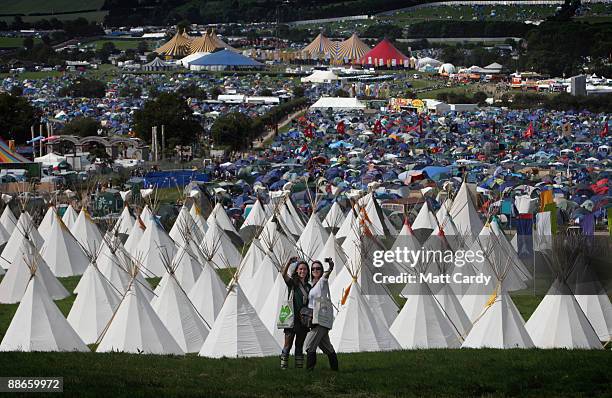 Two festival goers take a photograph of themselves in front of the tipi field as music fans start to arrive at the Glastonbury Festival site at...