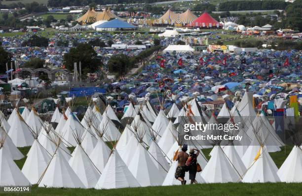 Two festival goers walk in front of the tipi field as music fans start to arrive at the Glastonbury Festival site at Worthy Farm, Pilton on June 24,...