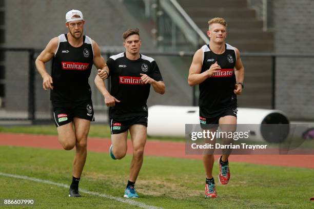 Ben Reid, Josh Thomas and Adam Treloar run laps during a Collingwood Magpies men's and women's joint AFL pre-season training session at the Holden...