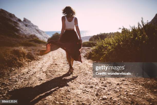 bohemian girl in skirt and crop top walking in nature - maroon flowers stock pictures, royalty-free photos & images