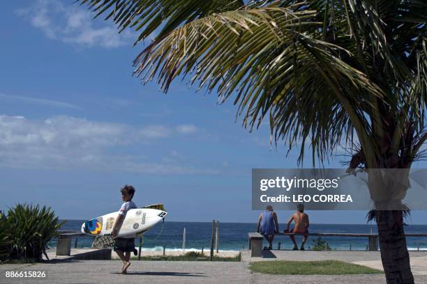 Young surfer Rickson Falcao heads to Saquarema's beach in Rio de Janeiro state, Brazil, on November 29, 2017. Despite its vast Atlantic coastline,...