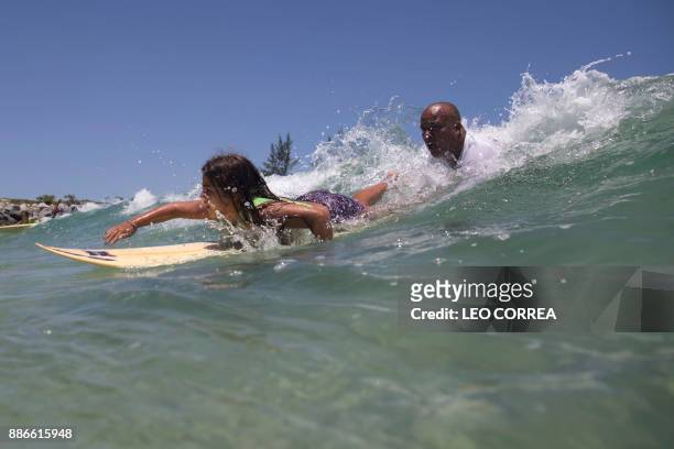 Luiz Augusto de Matos one of the teachers at Saquarema Surf School, helps his pupil Luana Felix to take a wave during a class in Saquarema, Rio de...