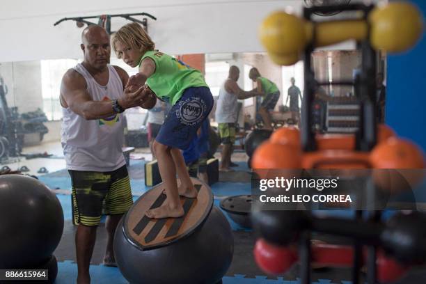 Luiz Augusto de Matos one of the teachers at "Saquarema Surf School", assists his pupil Miguel Cortinhas at the "Inside Fit" training centre during a...