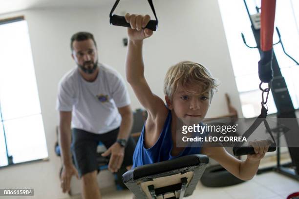 Diego Souza exercises with the assistance of his surfing teacher David Santos at the "Inside Fit" surf training centre in Saquarema, Rio de Janeiro...