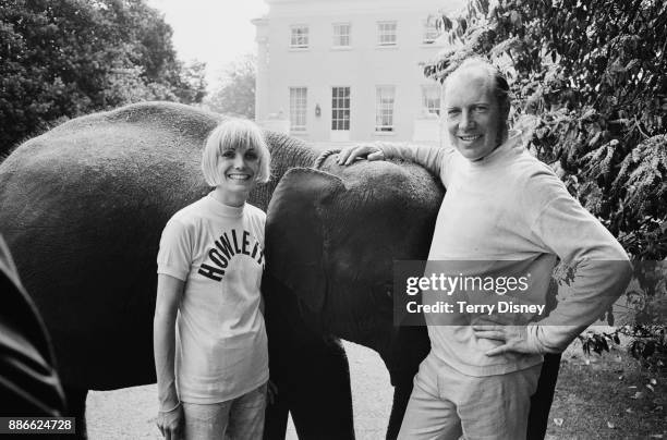 Zoo owner and gambling club host John Aspinall with future wife Lady Sarah-Marguerite Curzon and an elephant from his own zoo, UK, 3rd July 1971.