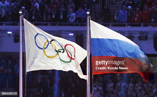 File photo shows the Olympic flag flying alongside the Russian flag at the 2014 Winter Olympics opening ceremony in Sochi, Russia, on Feb. 7, 2014....
