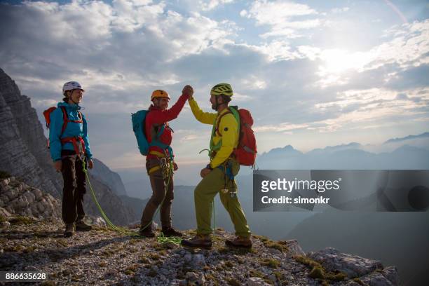 kletterer geben hohe fünfer auf berggipfel - bergsteiger gipfel stock-fotos und bilder