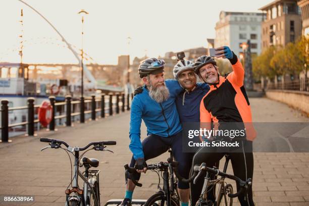 three senior men on racing bikes taking a selfie - waterfront lifestyle stock pictures, royalty-free photos & images