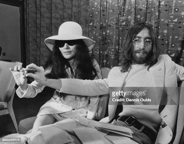 Singer and songwriter John Lennon of English rock band the Beatles and his wife Yoko Ono holding acorns during a press conference at Heathrow Airport...
