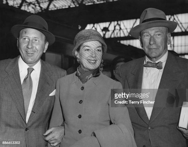 American actress Rosalind Russell arrives at Waterloo Station in London on the 'Queen Elizabeth' boat train, with her husband, producer Frederick...