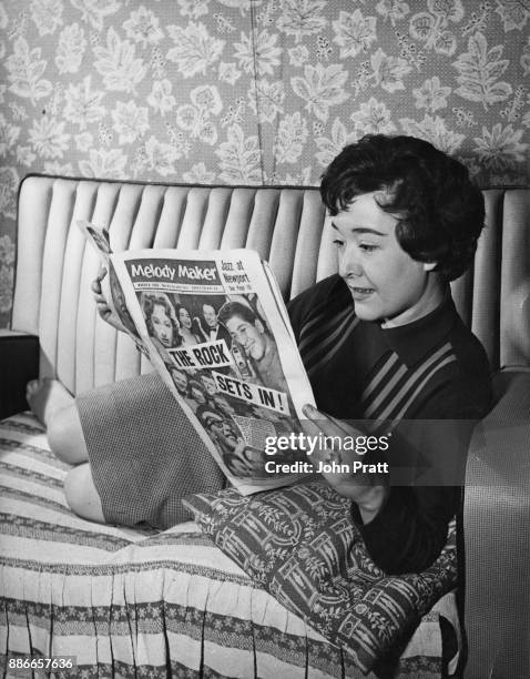 English singer Sheila Buxton reads music magazine 'Melody Maker' at home before leaving for a stage appearance, UK, March 1958.