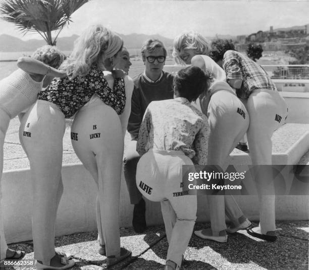 English actor Michael Caine, star of the film 'Alfie', surrounded by women promoting the film with their trousers, during the Cannes Film Festival,...