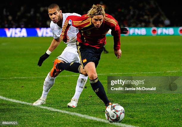 Fernando Torres of Spain beats the tackle of Oguchi Onyewu of USA during the FIFA Confederations Cup Semi Final match between Spain and USA at Free...