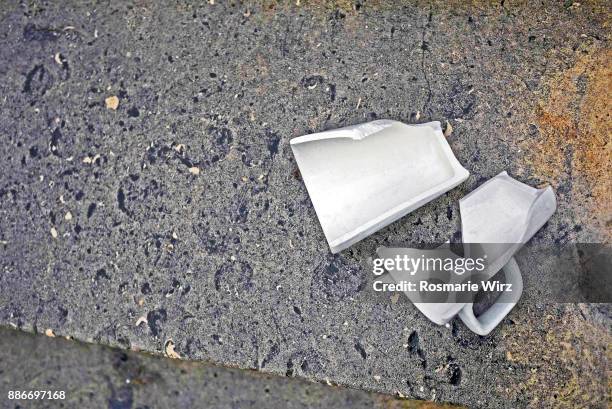 white broken china cup one stone pavement. - broken cup stock-fotos und bilder