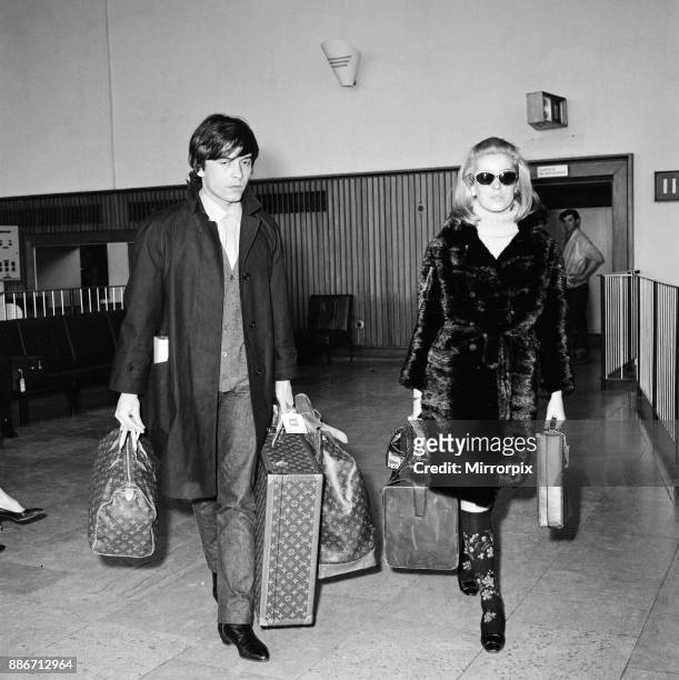 Catherine Deneuve, actress, and husband fashion photographer David Bailey arrive at London Airport from Paris. She is here for the Royal performance...