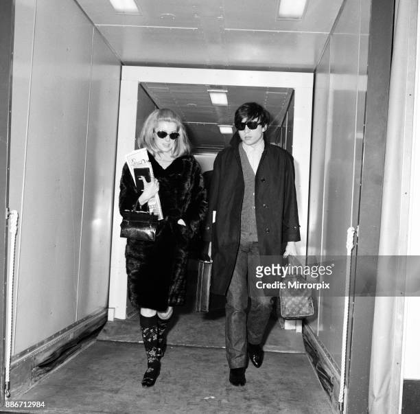 Catherine Deneuve, actress, and husband fashion photographer David Bailey arrive at London Airport from Paris. She is here for the Royal performance...