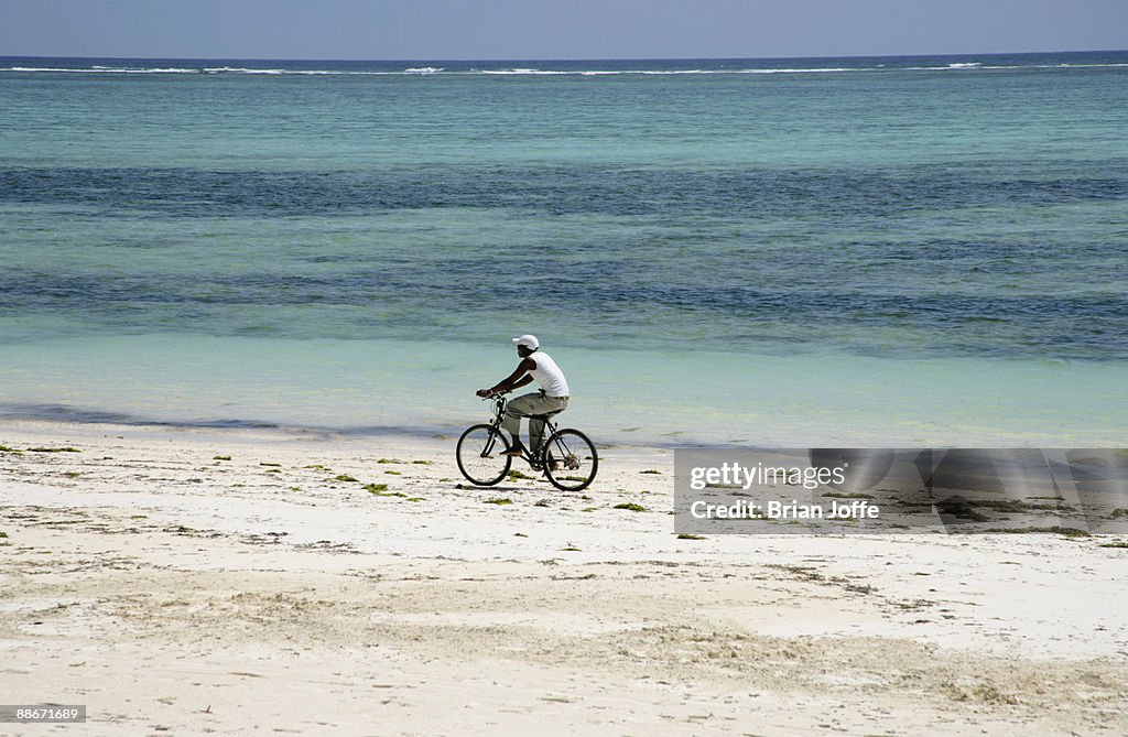 Man cycling on beach. Zanzibar