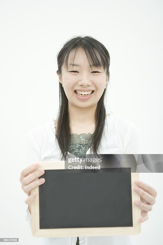 Young woman holding blackboard, smiling