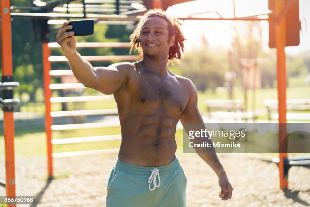 maschio a torso nudo che fa selfie mentre si allena nel parco - black male bodybuilders foto e immagini stock